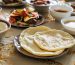 Close up of flat breads in a plate surrounded with other dishes